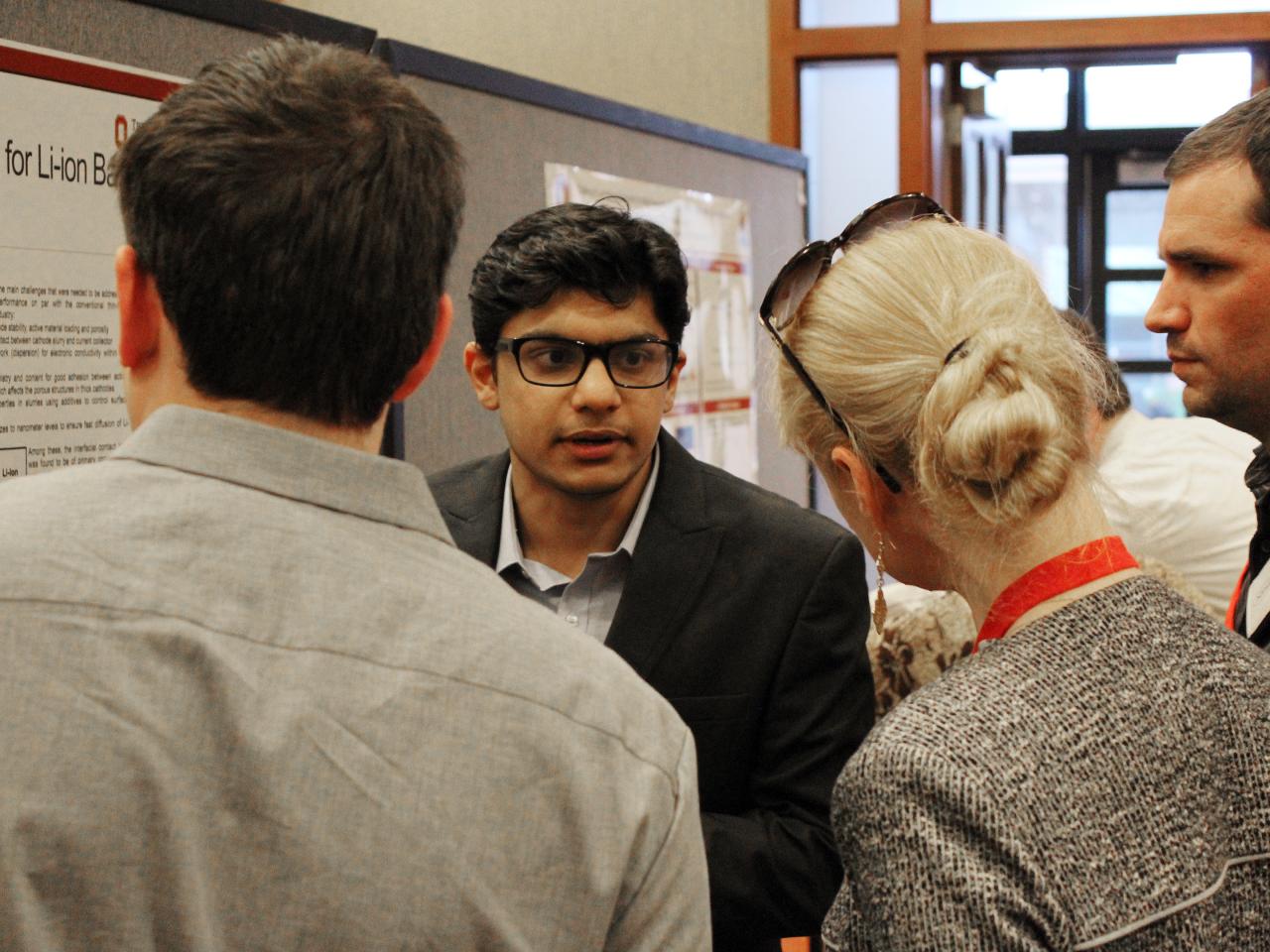 Two guests talking to poster presenter