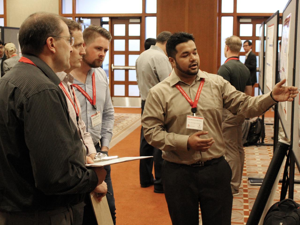 Man presenting his poster to two visitors