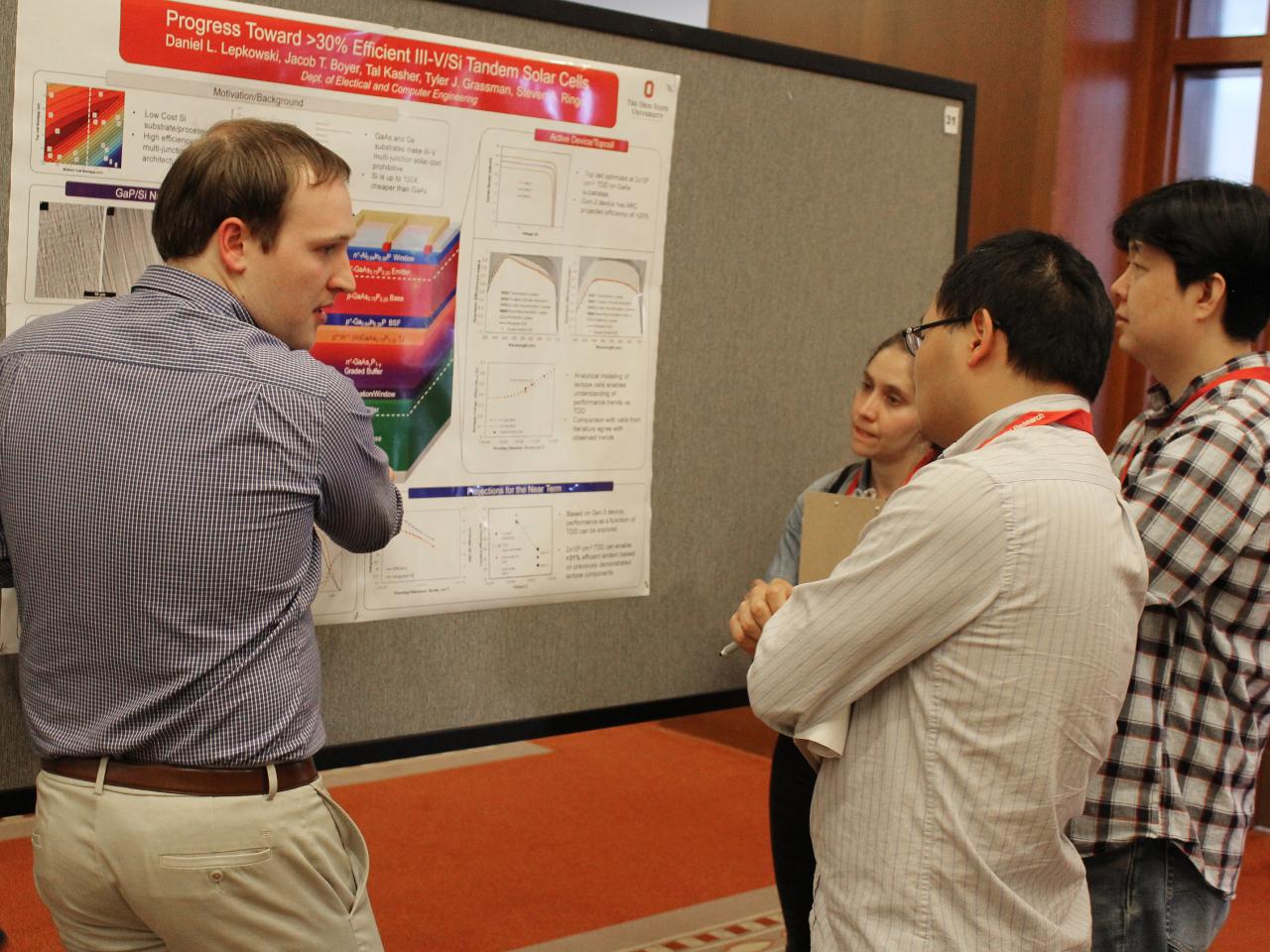 Group of three people discussing poster