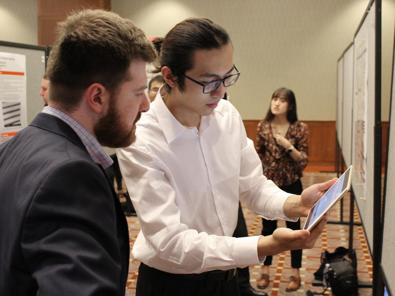 Man explaining his poster to visitor