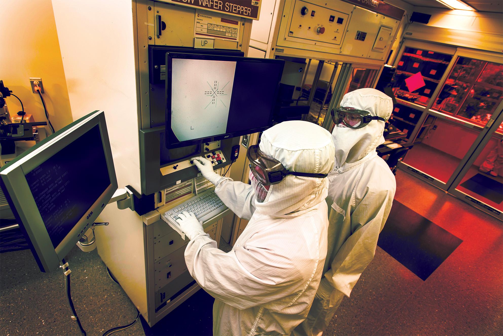 Two lab workers in white fully body suits