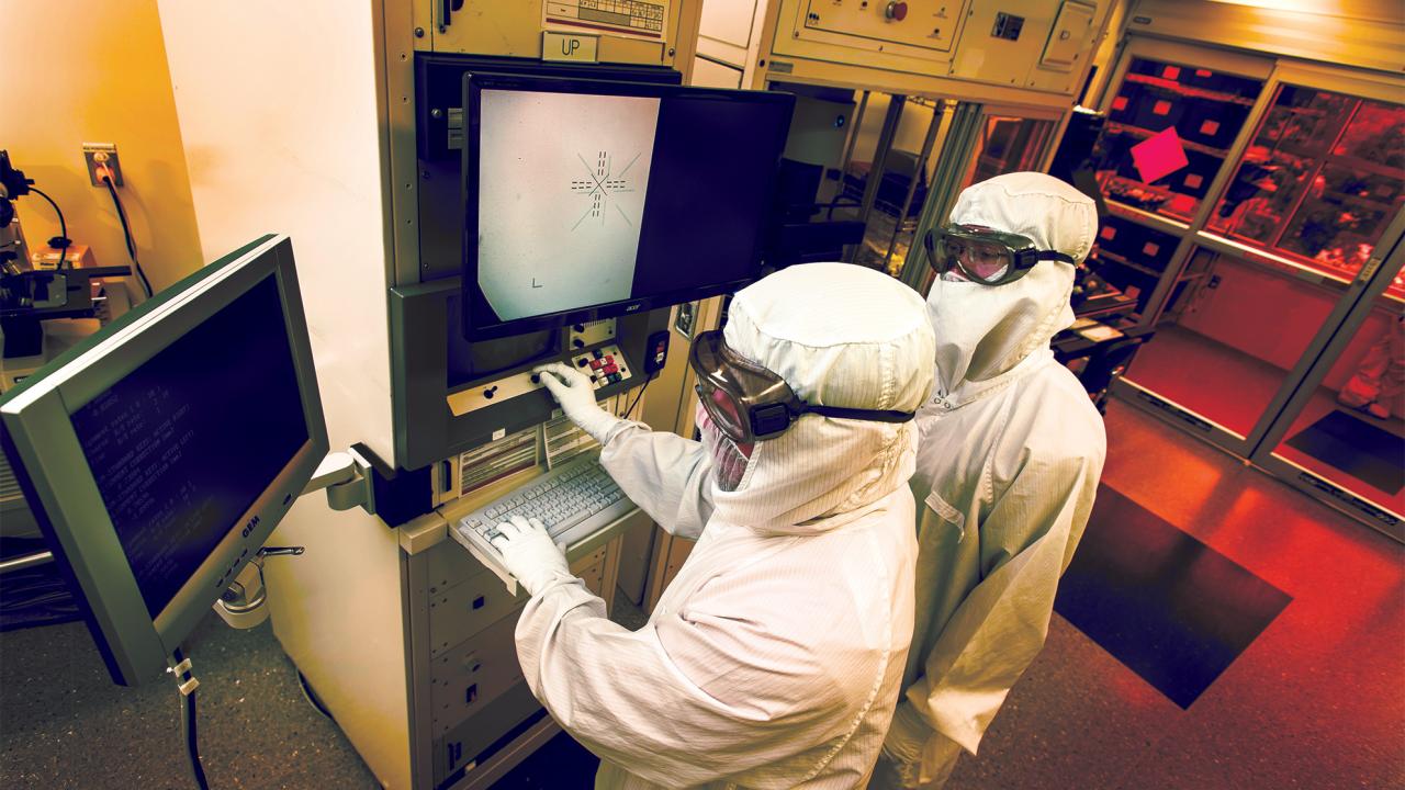 Two lab workers in white fully body suits